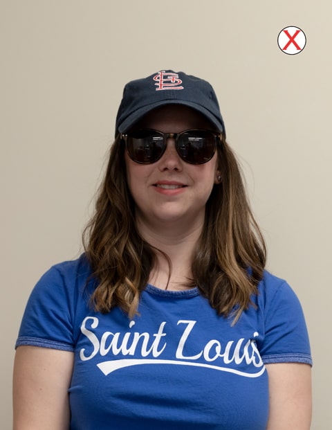 Example of bad accessories A headshot of a woman wearing a SLU t-shirt. She is wearing a baseball cap and dark colored sunglasses.
