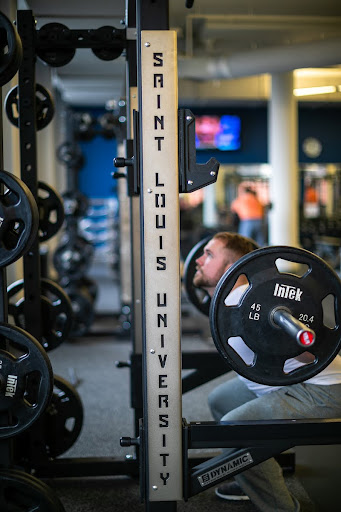 A man squats while lifting weights, with a bar bell over his shoulders.